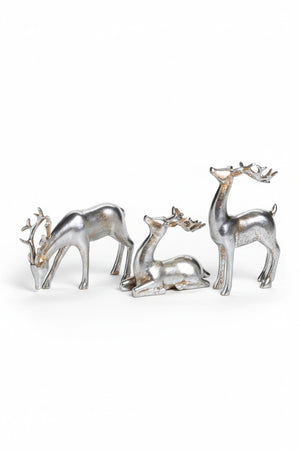 Three silver-colored ZODAX DECORATIVE SILVER REINDEER polyresin figurines in assorted styles on a mirrored tray with two gift boxes wrapped in white ribbon.