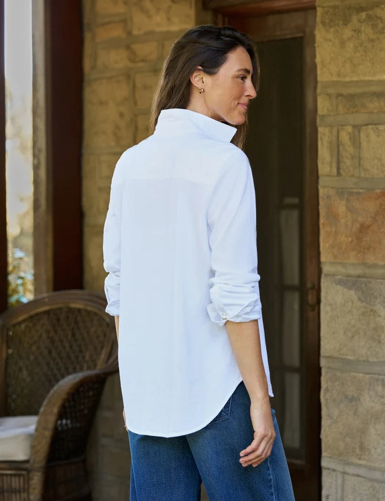 A woman with curly hair models the FRANK &amp; EILEEN WAVERLY NYC Button Up Shirt in Vintage Jersey White, shown indoors from shoulders to waist, hand on hip, highlighting its classic chest pocket.