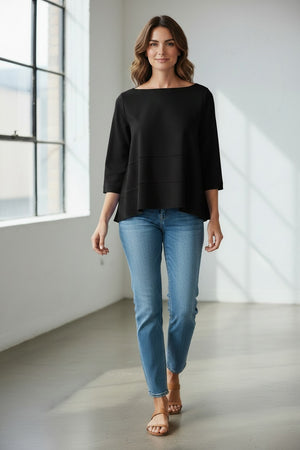 A person wears the MEIMEIJ Oversized Crew Neck Top in bright blue, featuring horizontal seam details, paired with gray pants, standing against a light textured background.