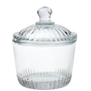 Two ETUHOME Bistro Glass Bon Bon Jars with ribbed lids sit on a wooden surface, one filled with yellow candies and the other nearly empty. Wrapped sweets are scattered nearby, creating a charming ETUHOME display.