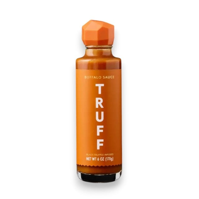 A 6 oz (170g) bottle of TRUFF - BUFFALO SAUCE from TRUFF HOT SAUCE, distinguished by its orange geometric cap and minimalist orange label with “TRUFF” and “Black Truffle Infused.” This sauce is infused with black truffle and balanced by the heat of cayenne.