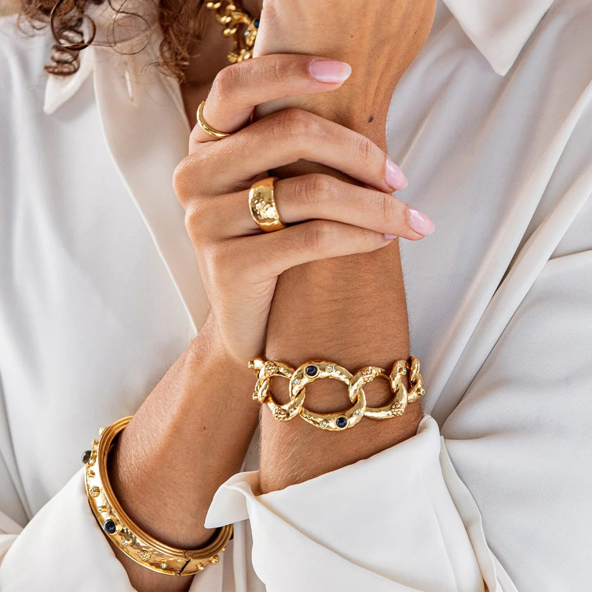The CAPUCINE DE WULF Cleopatra Ring Size 7 features a wide gold-finished design with a slightly hammered texture. Crafted from natural materials, this elegant, reflective ring is displayed on a plain white background, embodying the brand's commitment to sophisticated handmade jewelry.