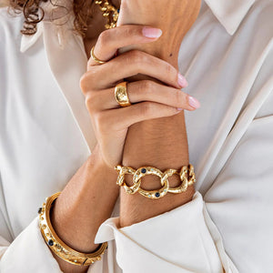 The CAPUCINE DE WULF CLEOPATRA RING SIZE 8, crafted in polished gold with a hammered texture, sits elegantly on a plain white background, highlighting the allure of handmade jewelry.