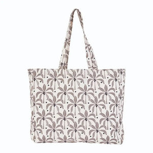 The ROCKFLOWERPAPER PALM SHOPPER TOTE BAG is a spacious cotton canvas bag with two handles, featuring a stylish brown palm tree print on a white background.