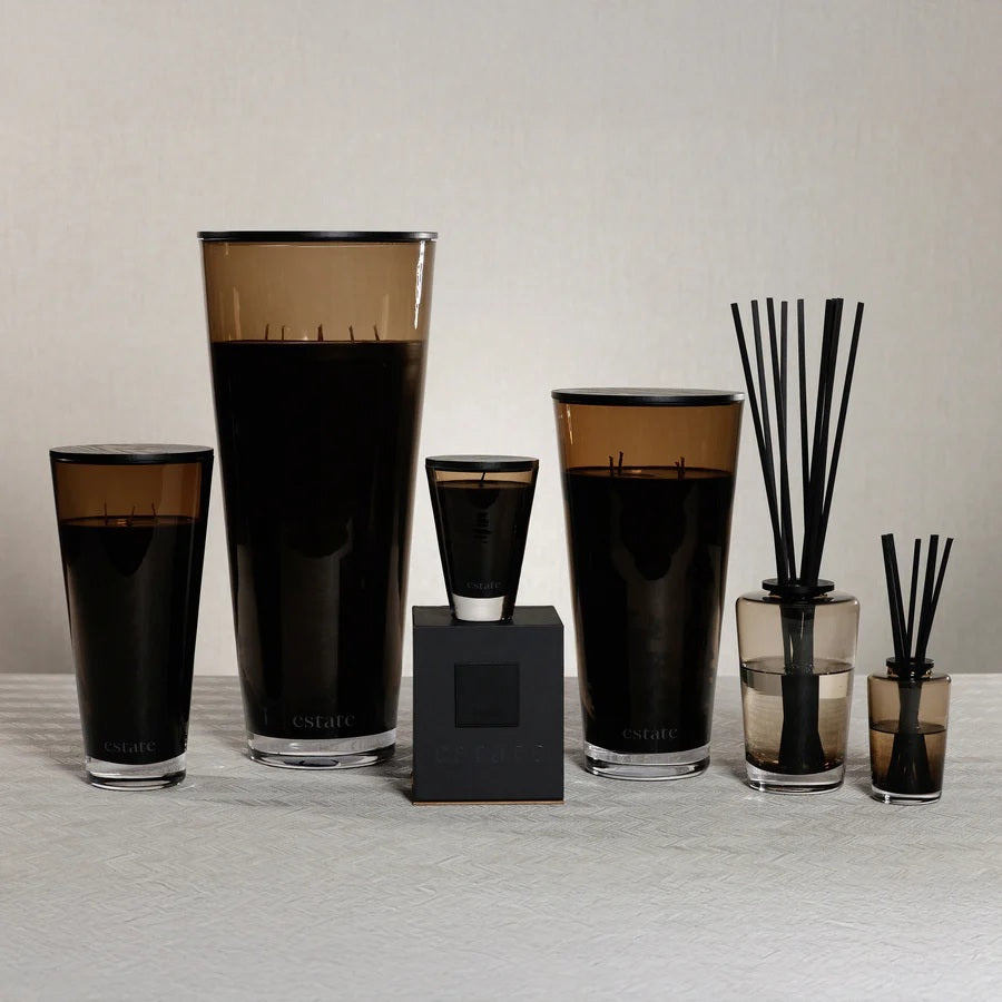 The ZODAX THISTLE ESTATE CANDLE - 57 OZ features a sleek, tall topaz glass design with an "estate" label, paired with a matte black rectangular box, capturing the essence of a California coast fragrance.