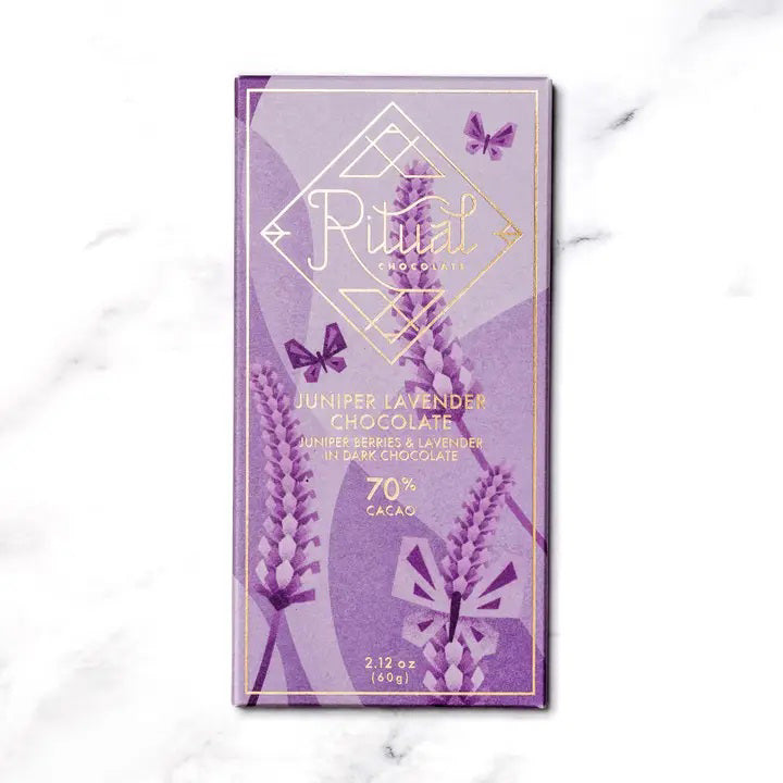 The RITUAL CHOCOLATE - JUNIPER LAVENDER CHOCOLATE bar by RITUAL CHOCOLATE features a purple wrapper with lavender, butterflies, and gold accents. This 70% cacao dark chocolate weighs 2.12 oz (60g) and includes juniper berries and lavender.