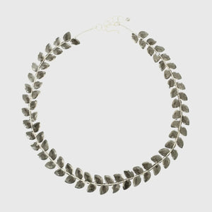 Shown from the shoulders up with their face partially out of frame, a person wears a textured, light beige fuzzy sweater and the ANN LIGHTFOOT Faceted Flat Herringbone Cut Smokey Quartz Necklace.