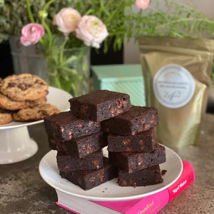 A white pouch labeled "MAISON ZOE FORD - BIG TIME BROWNIE MIX" features a clear window displaying rich, luxurious brownies with chunks inside. The packaging reads "Exceptional Baking Mixes - Meilleure Mélange À Cuisson", "12 Brownies," and has a net weight of 675g. Get ready to bake the best brownies worthy of Top Chef Canada!