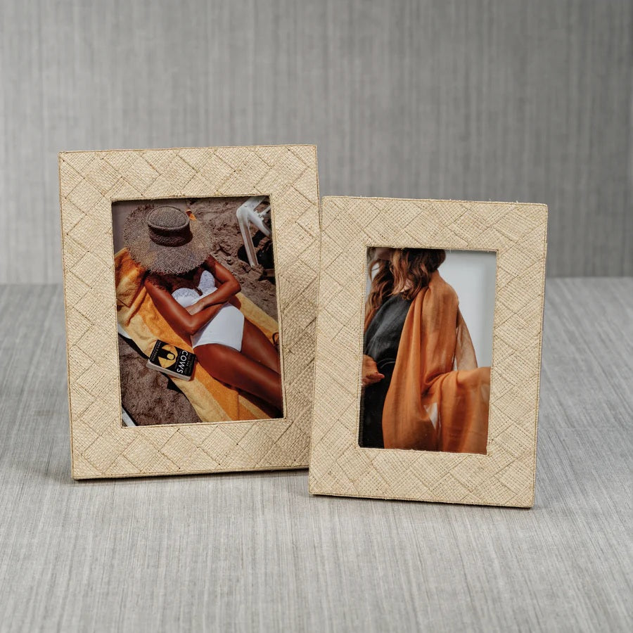 Showcasing the LA BOCCA WOVEN RAFFIA FRAME - 4X6 by ZODAX, this decorative beige frame features a textured woven raffia pattern and displays a portrait of a person draped in a sheer orange-brown shawl over a black outfit, partially turned away from the camera—perfect for introducing an organic touch of home decor to any space.