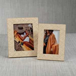 Showcasing the LA BOCCA WOVEN RAFFIA FRAME - 4X6 by ZODAX, this decorative beige frame features a textured woven raffia pattern and displays a portrait of a person draped in a sheer orange-brown shawl over a black outfit, partially turned away from the camera—perfect for introducing an organic touch of home decor to any space.