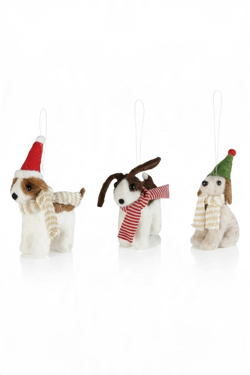 Three handcrafted FELT DOG ORNAMENT holiday decorations wearing festive hats and scarves perched atop a red plaid gift box.