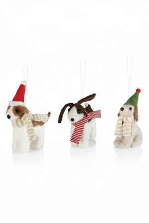 Three handcrafted FELT DOG ORNAMENT holiday decorations wearing festive hats and scarves perched atop a red plaid gift box.