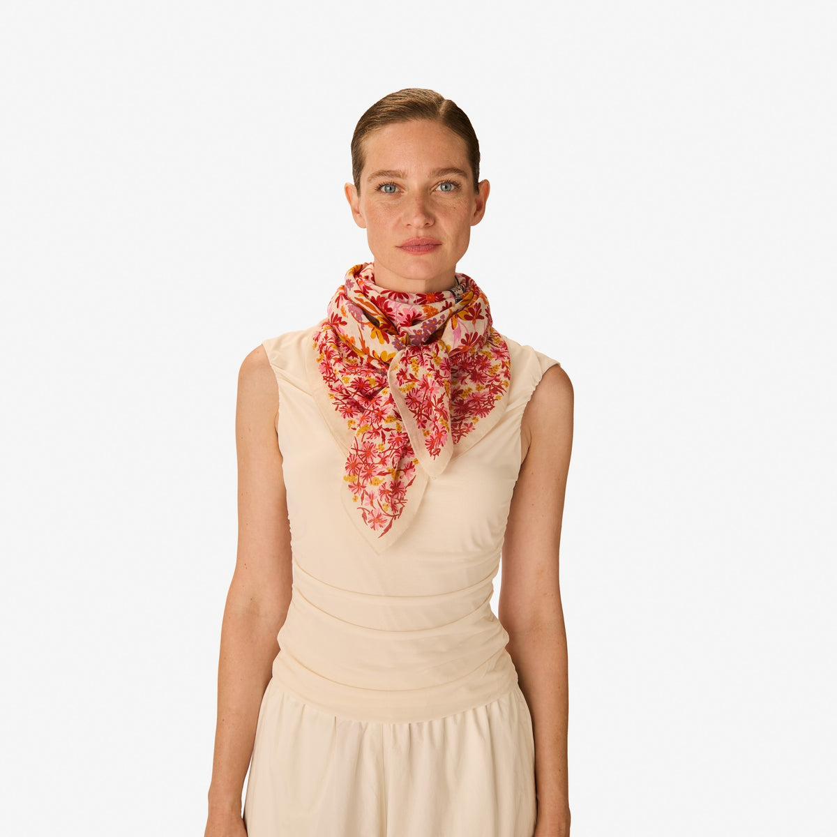 The INOUI EDITIONS - FAUST SCARF IN PINK by INOUI is a cotton square scarf decorated with red, yellow, and pink flowers plus illustrations of an open book, sunglasses, camera, hairbrush, photos, and tickets—a versatile accessory.