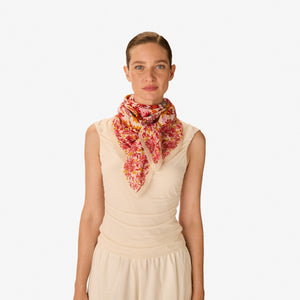 The INOUI EDITIONS - FAUST SCARF IN PINK by INOUI is a cotton square scarf decorated with red, yellow, and pink flowers plus illustrations of an open book, sunglasses, camera, hairbrush, photos, and tickets—a versatile accessory.