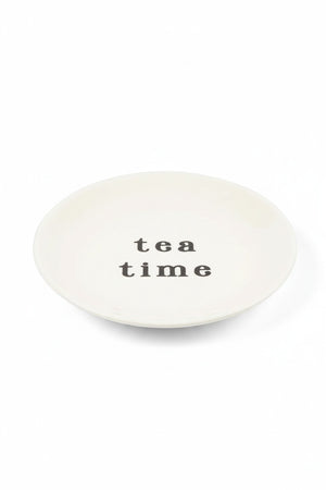 Small, round cream-colored TEA TIME SMALL CERAMIC PLATE with “tea time” printed in black in the center.