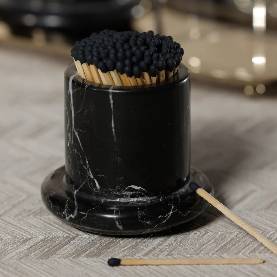 The ZODAX MARBELLA BLACK MARQUINA MARBLE MATCH STRIKE holds black-tip matches upright on a round black marble base, adding a touch of style to your space.