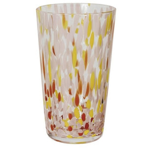 A selection of CREATIVE COOP HAND-BLOWN CONFETTI DRINKING GLASS tumblers, each with red, yellow, and pastel speckles, is displayed on a light surface; a tall glass holds drink stirrers and a cocktail recipe card.