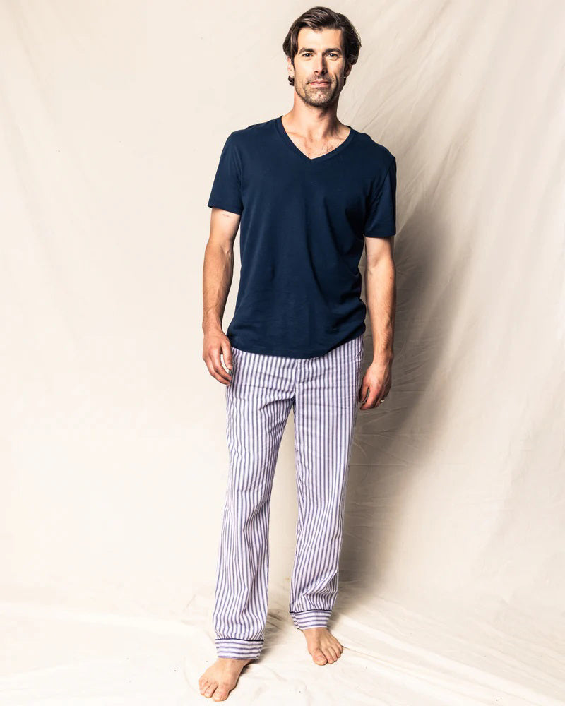 The FEARRINGTON LIFESTYLE COLLECTION - MEN&#39;S TWILL PAJAMA PANT IN NAVY FRENCH TICKING by PETITE PLUME is a pair of pajama pants adorned with white and blue vertical stripes. Made from the finest quality cotton, these luxurious pants feature a black drawstring waist and black trim at the cuffs. Laid flat on a white background, they proudly display their elegant French ticking design.