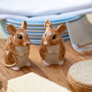 The QUAIL CERAMICS Wood Mouse Salt and Pepper Set by QUAIL DESIGNS features two hand-painted brown and white stoneware mice figurines with large ears, black eyes, and tiny paws, standing upright side by side.