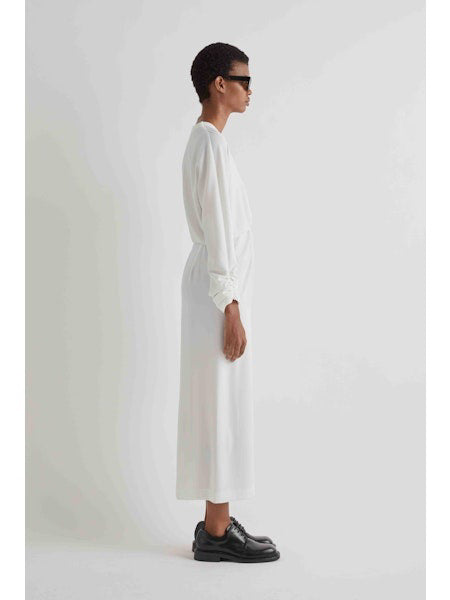 A person in dark sunglasses, black chunky shoes, and the MEIMEIJ Gathered Waist Long Sleeve Dress stands against a plain white background.