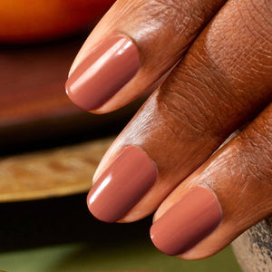 A chart displaying twelve lipstick shades—each swatched alongside its name and color description—features a range of reds and oranges, from coral and cherry to terracotta, pomegranate, and deep berry tones. These hues are designed to perfectly complement your favorite vegan nail polish or pair flawlessly with MANUCURIST - GREEN™ NAIL POLISH IN BRICK by MANUCURIST INC for a coordinated, striking look.