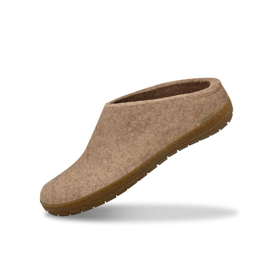 The GLERUPS - SLIP ON SHOE WITH RUBBER SOLE IN SAND by GLERUPS, a beige wool slipper with a closed toe and natural rubber sole, is shown slightly elevated against a white background with a faint shadow beneath.