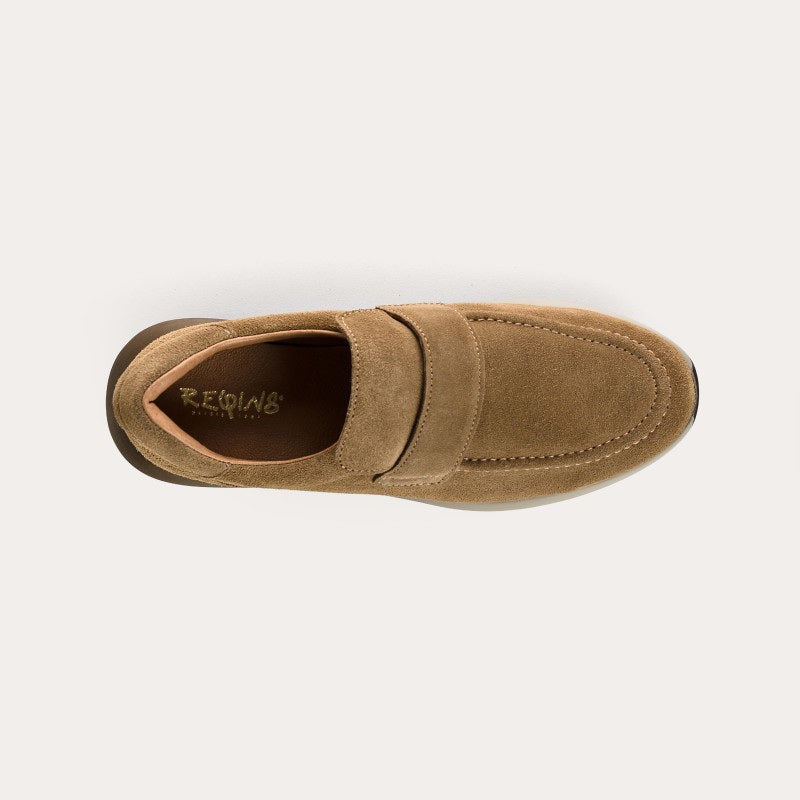 The REQINS - CARABEL Suede Sneaker in Havana is a tan goat suede casual-chic slip-on trainer featuring a rounded toe, wide instep strap, cushioned collar, and a thick dark rubber sole with a textured tread; shown in profile on a white background.