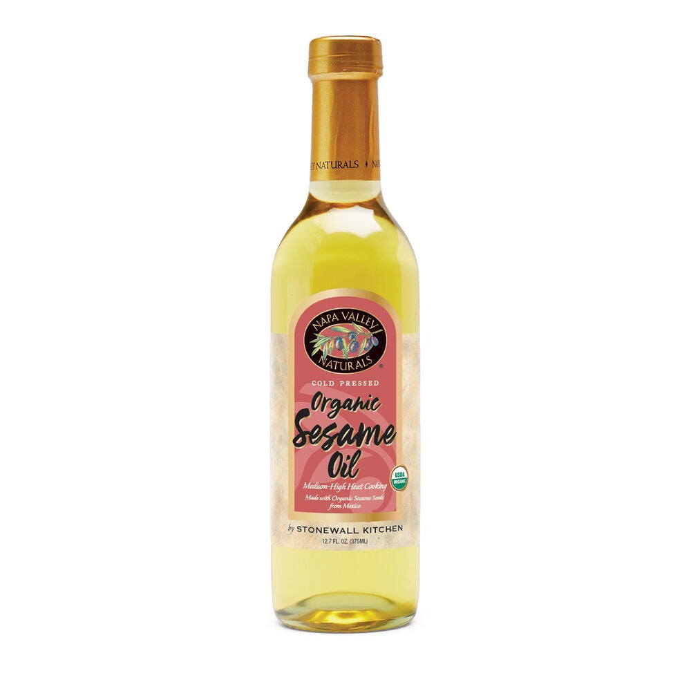 A clear glass bottle of Stonewall Kitchen Organic Sesame Oil with a gold cap and a pink label, displaying the brand and product information—ideal for allergy-friendly cooking.