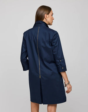 A woman with straight brown hair models the HINSON WU - ALESSA 3/4 SLEEVE DRESS IN STRETCH POLISHED COTTON NAVY, featuring a boxy fit, knee-length cut, three-quarter sleeves, and a visible back gold zipper against a plain background.