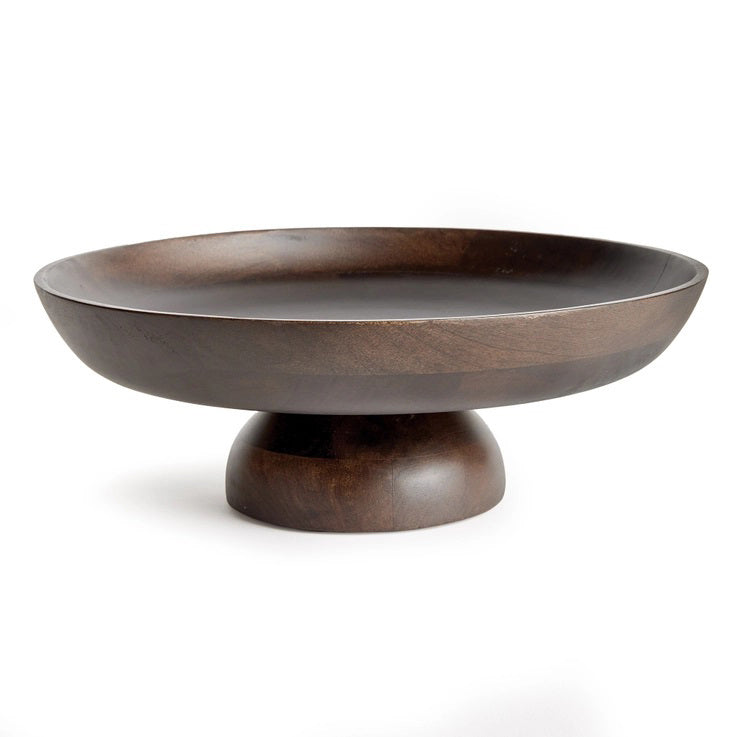 The NAPA HOME AND GARDEN - BOWIE FOOTED BOWL features a dark mango wood pedestal design with a wide, shallow bowl and sturdy base. Its smooth finish showcases natural grain patterns, merging classic craftsmanship with contemporary style against a plain white background.