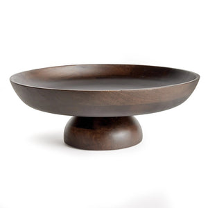The NAPA HOME AND GARDEN - BOWIE FOOTED BOWL features a dark mango wood pedestal design with a wide, shallow bowl and sturdy base. Its smooth finish showcases natural grain patterns, merging classic craftsmanship with contemporary style against a plain white background.