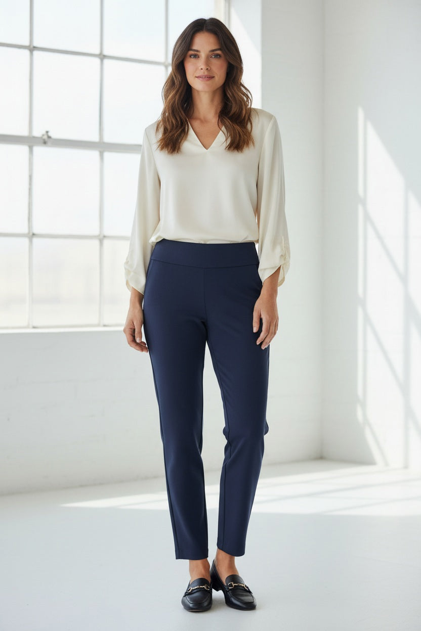 Wearing the KRAZY LARRY, INC PULL ON STRAIGHT LEG MICROFIBER PANT in white, paired with a dark patterned top and red shoes, a person poses against a white background. The image features only the lower half of their body, highlighting this chic office-ready style.