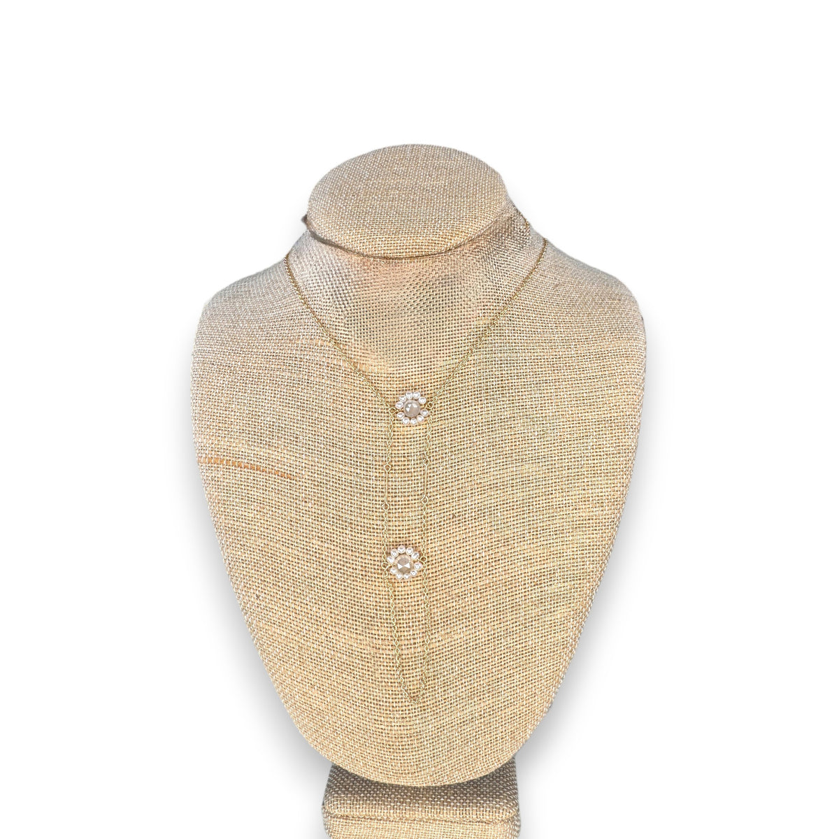 The GOLDISH &quot;Floral White Moonstone with White Pearls Ladders to Bliss&quot; necklace features two flower-shaped moonstone pendants and delicate white pearls, shown on a beige jewelry stand against a white backdrop.