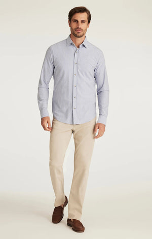 A man with light brown hair and a beard wears a tan blazer, brown sweater, white collared shirt, 34 HERITAGE - CHARISMA RELAXED STRAIGHT LEG PANT IN DAWN TWILL by 34 HERITAGE, and brown shoes against a plain white background.