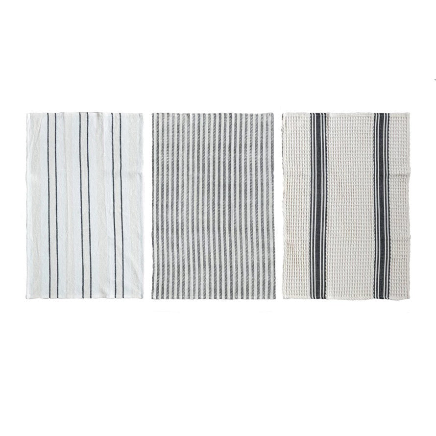 Three CREATIVE COOP WOVEN COTTON SLUB TEA TOWELS are laid flat, each with a unique vertical striped pattern in varying textures and stripe widths, in shades of white, gray, and black.