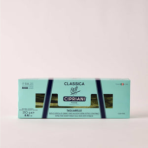 A close-up view of uncooked CIPRIANI - ORGANIC EGG TAGLIARRELLE PASTA WITH SPINACH from ATALANTA CORPORATION. The green-colored egg pasta strands, reminiscent of artisanal pasta, are coated with flour and are arranged in a slightly overlapping manner, showcasing their flat and wide shape.