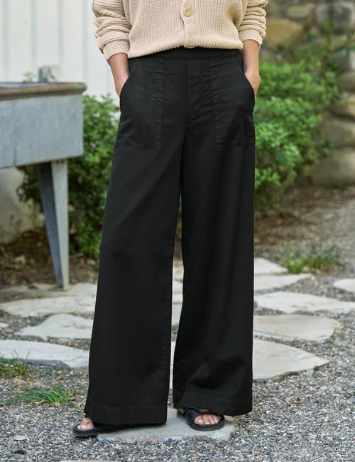 A person wearing the FRANK & EILEEN Madeline Patch Pocket Pull On Pant in Famous Denim Black styled with a beige knit sweater, shown from waist to mid-thigh.