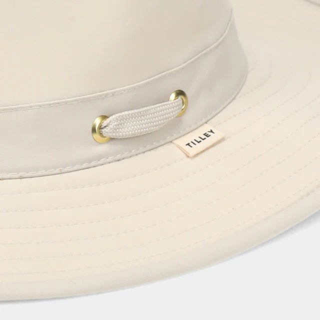 The TILLEY AIRFLO BROAD BRIM HAT LTM6 in Light Stone is a recycled nylon sun hat with UPF 50+ protection, wide brim, mesh ventilation near the crown, and a small band tag. Shown on a plain white background.