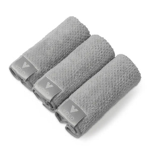 Three VOLO BEAUTY Face Towels from the Pack of 3 are rolled side by side on a white background, each showing a gray tag with the white logo and text, accentuating their luxury Nanoweave fabric.