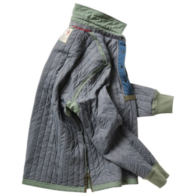 The RELWEN Polo-Jack in Muted Olive, a long-sleeve quilted technical popover featuring a chest pocket, buttoned collar, and cuffs, is shown laying flat on a white background.