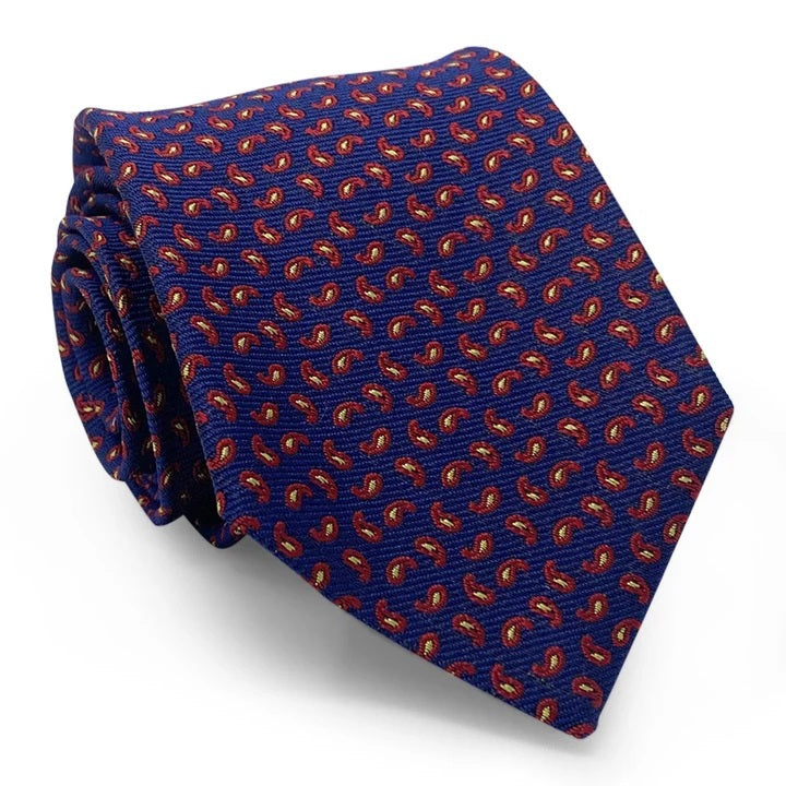 A rolled-up Camden Silk Tie in navy by Bird Dog Bay, featuring a red and yellow paisley pattern and complete with a Peter-Blair woven label, displayed on a white background.