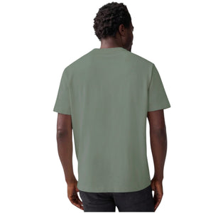 A person wears the MACK WELDON Heavyweight Slub Cotton Pocket T-Shirt in Cactus, a light olive green relaxed fit short-sleeve tee with a chest pocket, shown cropped to the upper torso against a plain white background.