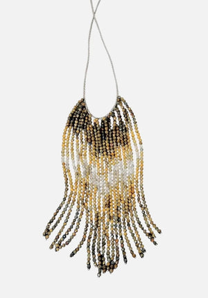 A mannequin wears a textured, curly taupe jacket and the ANN LIGHTFOOT Tiger Eye and Quartz Ombre Cascade Necklace, featuring dramatic dark beaded fringes in a triangular shape. The softly blurred background is neutral.