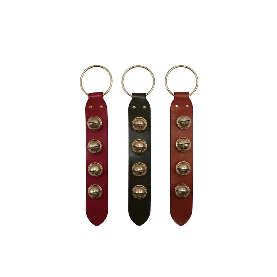The LEATHER AND BELL DOOR HANGER by CREATIVE COOP comes in red, black, and brown leather with gold keyrings and studs—offering a classic door hanger look for a stylish way to accent your keys or bag.