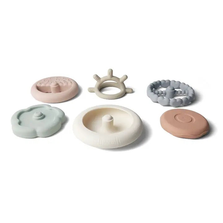 Introducing the SILICONE SUN STACKING RING TOWER from ALI + OLI: a set of BPA-free silicone stacking rings in soft pastel hues. The rings come in various shapes and textures, including hearts, and feature a sun-shaped topper on a sturdy base. This baby development toy is designed to promote motor skills and creativity.