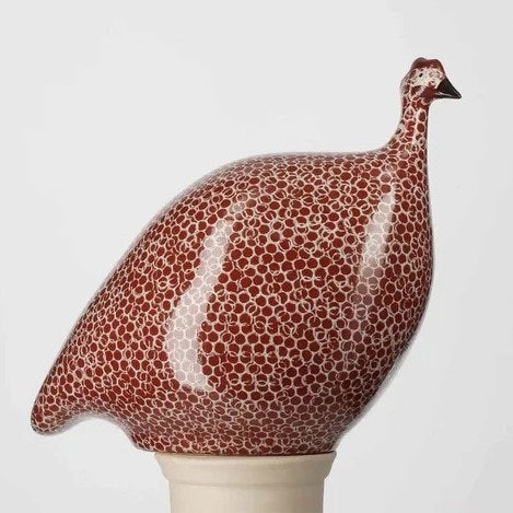 The LES CERAMIQUES DE LUSSAN Medium Ceramic French Guinea in Bordeaux Spotted White, featuring a rounded body inspired by French guinea hens, is displayed on a white pedestal against a plain light background.