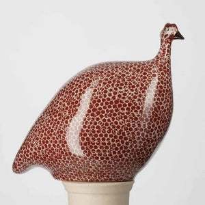 The LES CERAMIQUES DE LUSSAN Medium Ceramic French Guinea in Bordeaux Spotted White, featuring a rounded body inspired by French guinea hens, is displayed on a white pedestal against a plain light background.