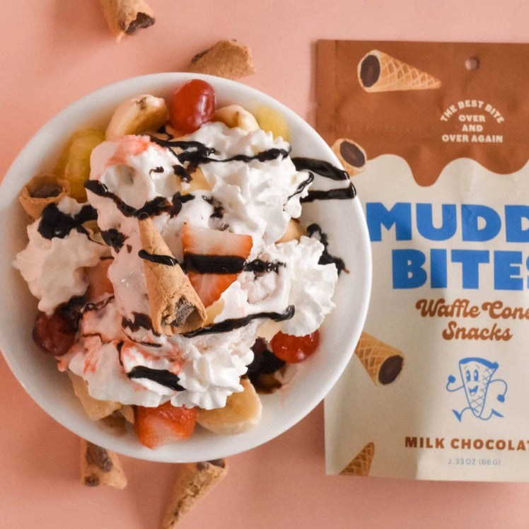 A bag of MUDDY BITES- MILK CHOCOLATE WAFFLE CONES against a brown background. The resealable packaging features the slogan "The Best Bit Over and Over Again" and boasts a 365+ day shelf life. This GMO-free product is also Kosher certified (D).