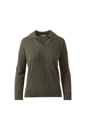 A woman stands against a white background, wearing the KINROSS CASHMERE Splitneck Polo in cashmere. She pairs it with matching pants, poses relaxedly while holding the hem of her top, and smiles softly.