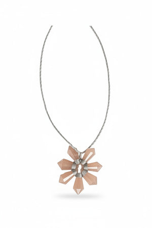 The ANN LIGHTFOOT - PEACH MOONSTONE SEVEN POINT FLOWER NECKLACE features a thin, gray braided cord and a pendant with light pink peach moonstone crystal points in a flower-like arrangement.